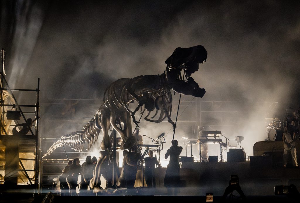 T-Rex puppet waits in the wings before it head's onto Coachella stage. Smoke and dark lighting creates a dynamic and dramatic shot.